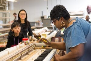 Photo of a Steinway craftswoman working on a keyboard.