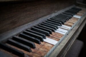 A beaten up piano keyboard with missing ivories.