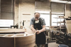 Steinway & Sons craftsman working on grand piano's rim